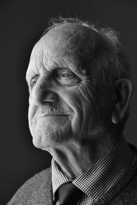 Close-up of smiling senior man against black background