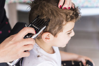 Cropped hands of hairdresser cutting boy hair