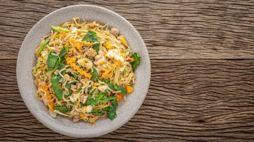 Stir fried instant noodles with pork, egg, chinese kale, carrot and pepper in crazing ceramic plate