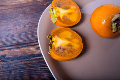 Persimmon cut into halves on a plate on a wooden table,copy space,closeup