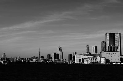 City at waterfront against cloudy sky