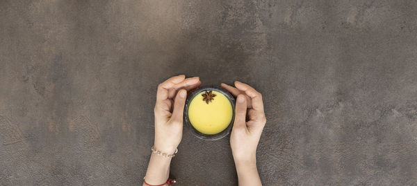 Midsection of woman holding apple against wall