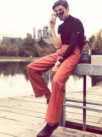 Full length of young man sitting by lake