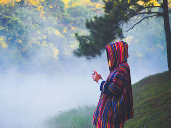 Woman holding multi colored umbrella standing on field