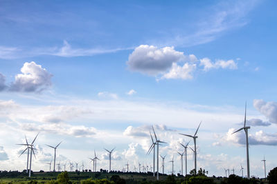 Wind turbines on field against sky