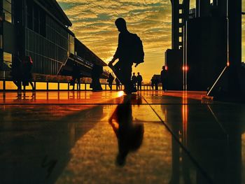 Silhouette man walking on road against sky during sunset