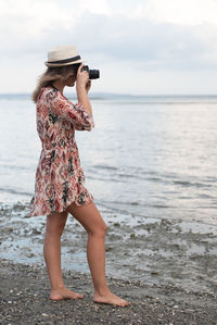 Full length of woman standing at beach against sky