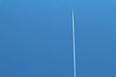 Low angle view of airplane flying against clear blue sky