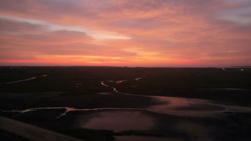 Scenic view of landscape against dramatic sky during sunset
