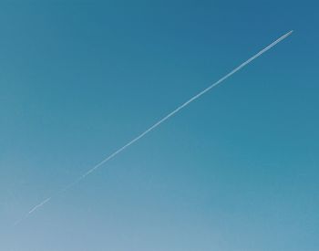 Low angle view of vapor trail against clear blue sky