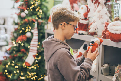 Boy holding stuffed toy while standing in store