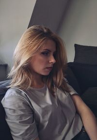 Close-up of thoughtful woman looking away while sitting on sofa at home