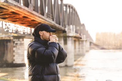 Man standing on bridge in city during winter