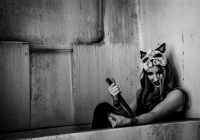 Portrait of woman sitting against wall