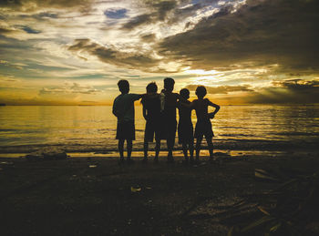 Silhouette people on beach against sky during sunset