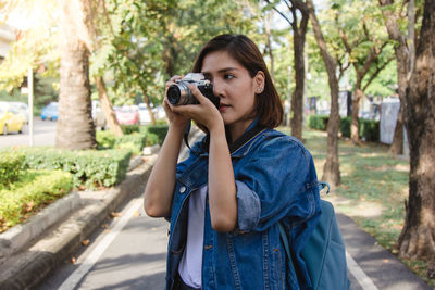 Portrait of young woman photographing through camera
