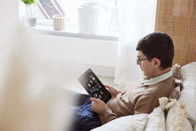 Teenage boy sitting on sofa and using tablet