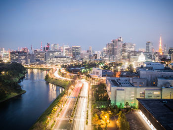 High angle view of illuminated city by buildings against sky