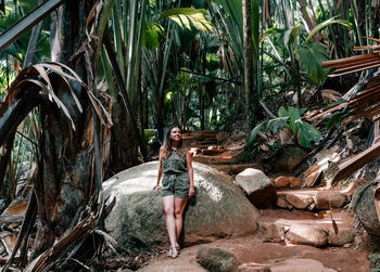 Woman standing on rock against trees in forest