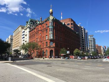 Road by buildings against blue sky