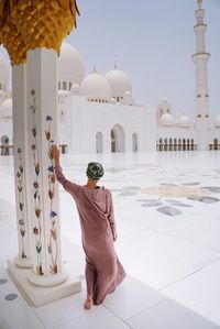 Rear view of mid adult woman standing by architectural column in mosque