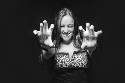 Portrait of woman gesturing while standing against black background
