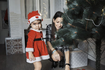 A mother and daughter decorate the christmas tree