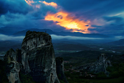 Distant person on top of the mountain against dramatic sky