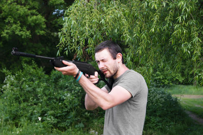 Man holding gun against plants