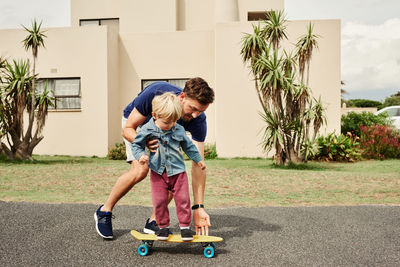 Father and son playing on skateboard outdoors