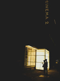 Silhouette man standing in illuminated city at night