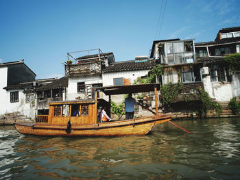 People on boat in river against buildings