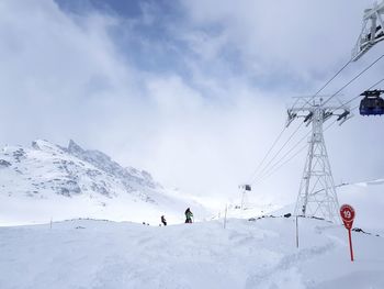 Low angle view of people on snowcapped mountain against sky