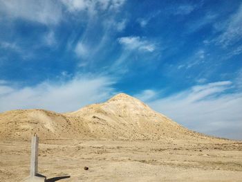 Low angle view of mountain against cloudy blue sky on sunny day