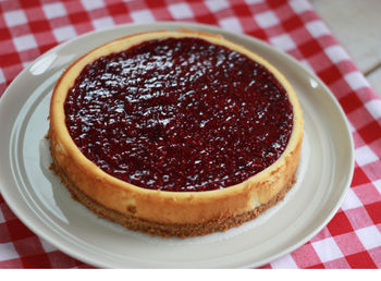 Whole cheesecake with raspberry on a white plate