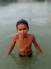 Portrait of shirtless boy swimming in water