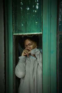 Portrait of cute girl standing against door