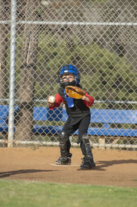 Young boy in catchers gear waiting at home plate to tag out a runner