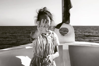 Teenage girl showing stop sign while standing in boat