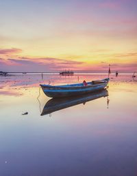 Boat moored in sea against sky during sunset