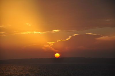 Scenic view of sea against dramatic sky during sunset