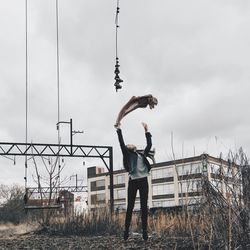 Man with arms raised against sky