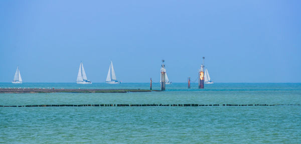 Sailboat in sea against clear blue sky