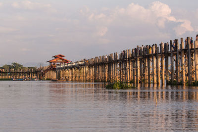 Bridge over river by buildings against sky