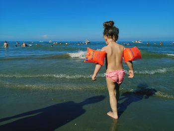 Rear view of woman on beach against sky