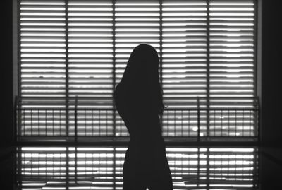 Silhouette woman standing by window at home