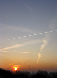 Scenic view of vapor trails in sky during sunset