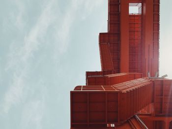 Directly below view of red metallic staircase against sky