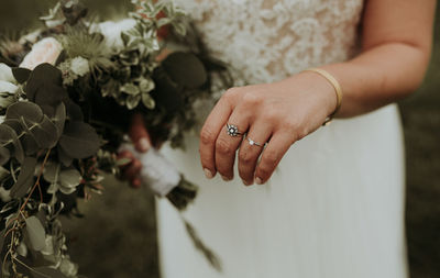 Midsection of bride with bouquet standing on land