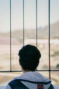 Rear view of man looking through window